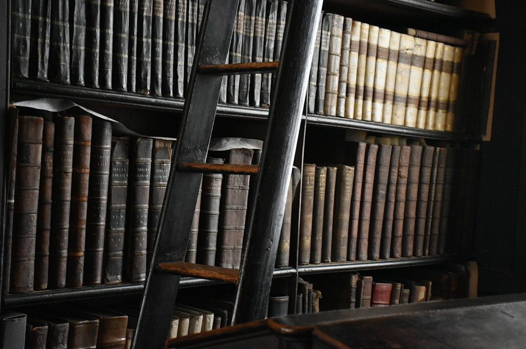 Tall wooden library shelves filled with old books